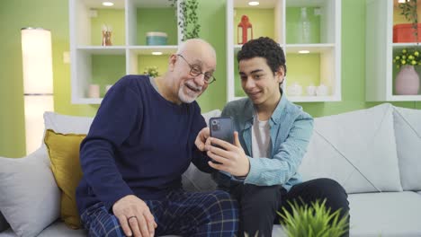 Young-grandson-informing-his-elderly-grandfather-about-technology.-Phone-use.